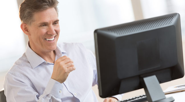 An older smaller business gentleman smiling at his computer screen due to the ease of our services.